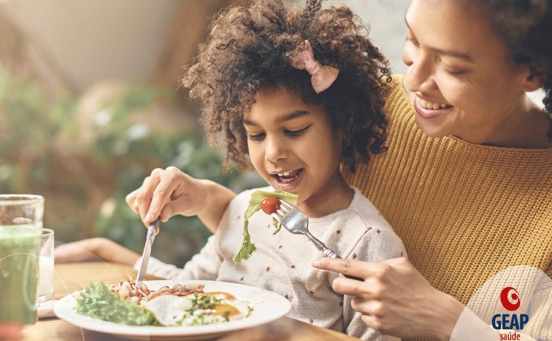 Mãe dando comida para filha